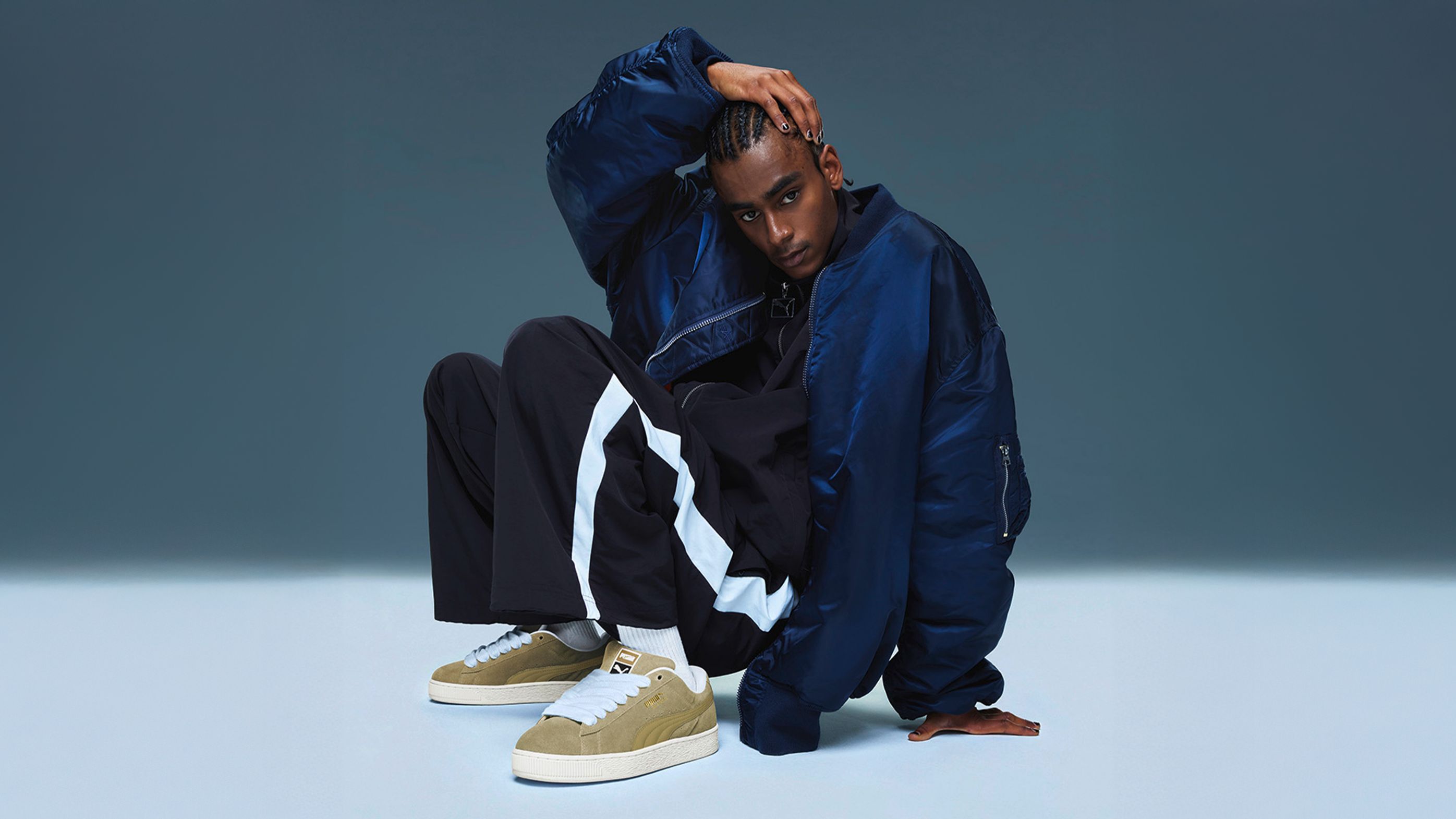 Malemodel posing in FENTY x PUMA 80s streetwear, styled with Suede XL.